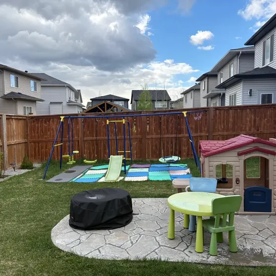 Patio trasero con columpios y casa de juegos